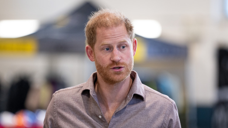 Prince Harry of Wales stares to the side in tan shirt