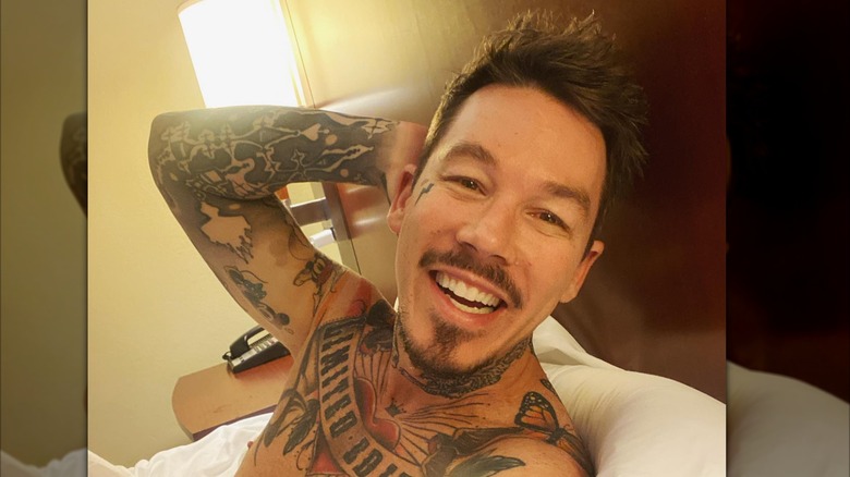 David Bromstad smiling and raising one arm behind his head