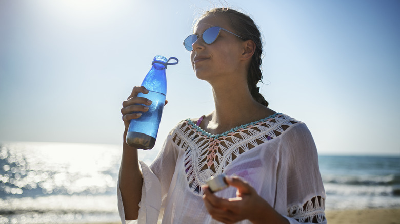 Woman drinking water at beach