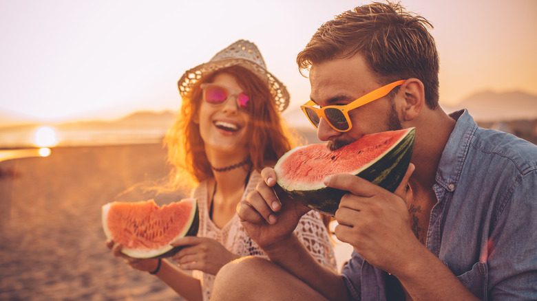 Couple eating watermelon at beach