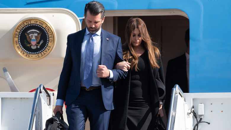 Donald Trump Jr. and Kimberly Guilfoyle looking somber exiting Air Force One