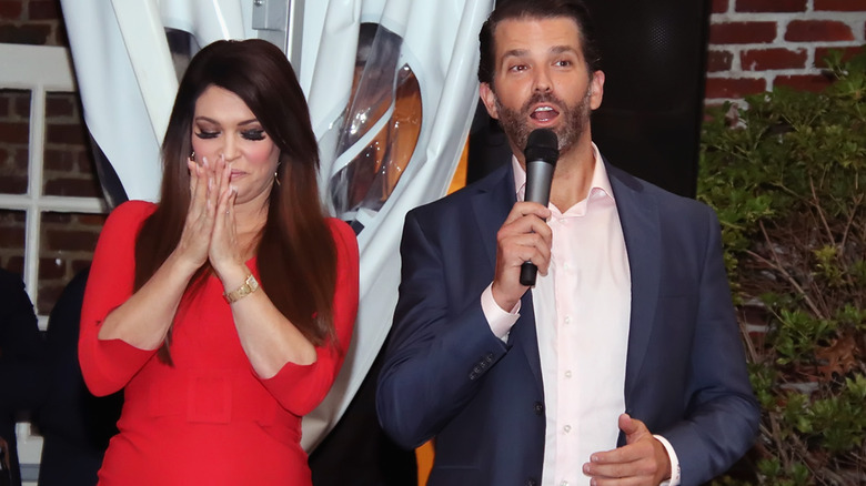 Kimberly Guilfoyle eyes closed hands together, Donald Trump Jr. speaking into microphone