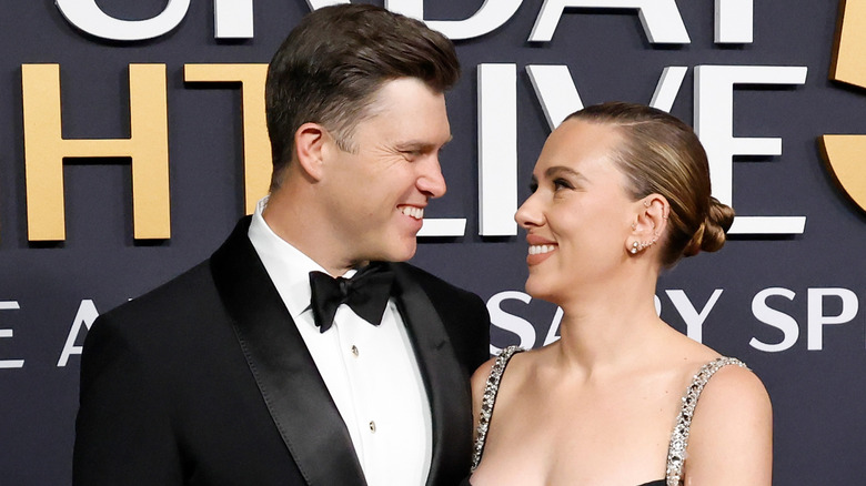 Colin Jost and Scarlett Johansson smiling at each other