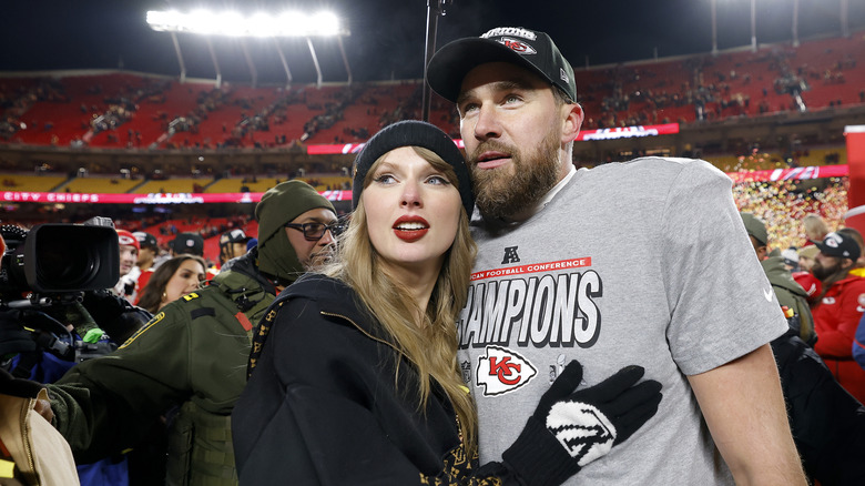 Taylor Swift and Travis Kelce smiling on the football field