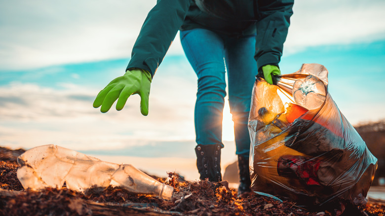 woman picking up trash on a beach