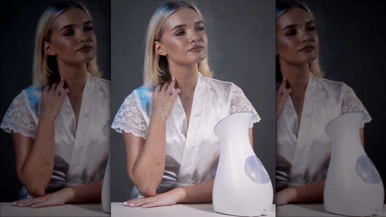 Woman using facial steamer for skincare 