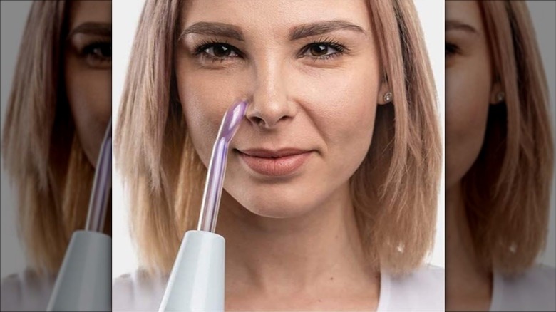 Woman using wand for facial 