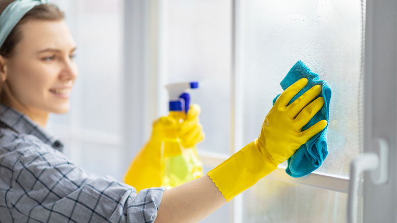 Woman cleans window with vinegar solution 