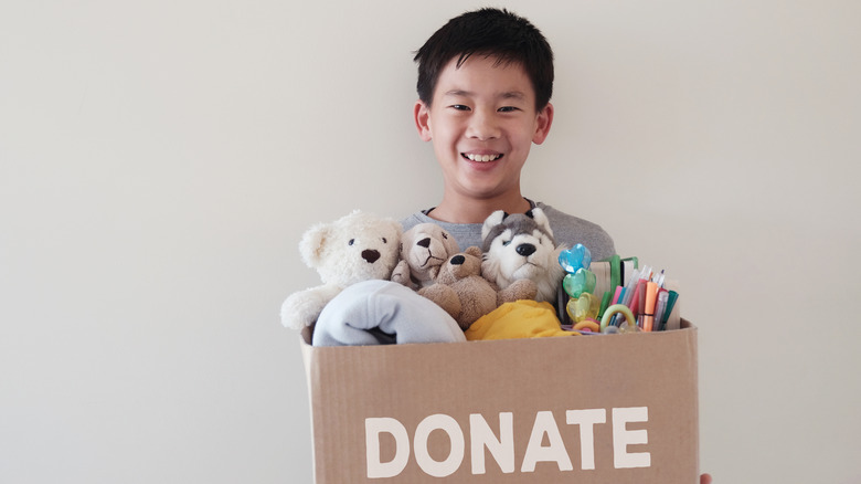 child holds box labeled "donate"