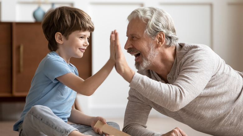 older man high-fives child in blue shirt 