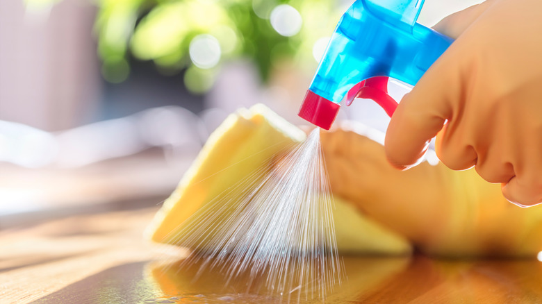 person sprays and wipes-down disinfectant spray