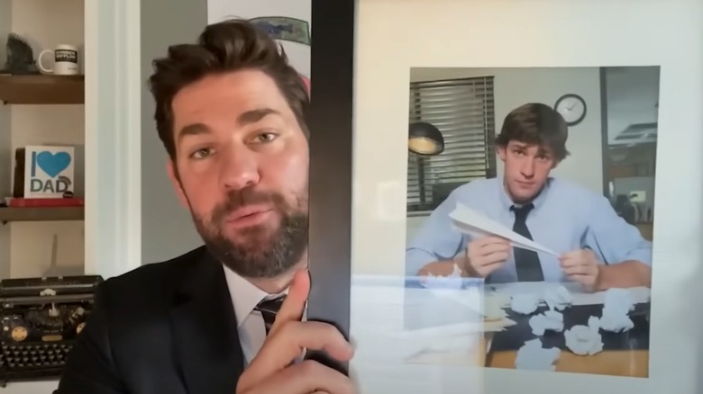 John Krasinski holding a photo of himself as Jim from 'The Office' in 'Some Good News'