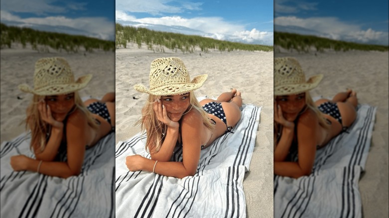 Olivia Dunne lying on beach in cowboy hat 