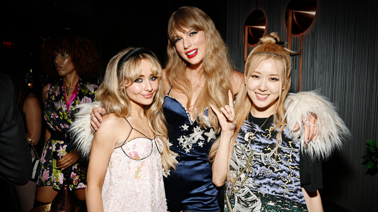 Taylor Swift smiling with her arms around Sabrina Carpenter and Rose