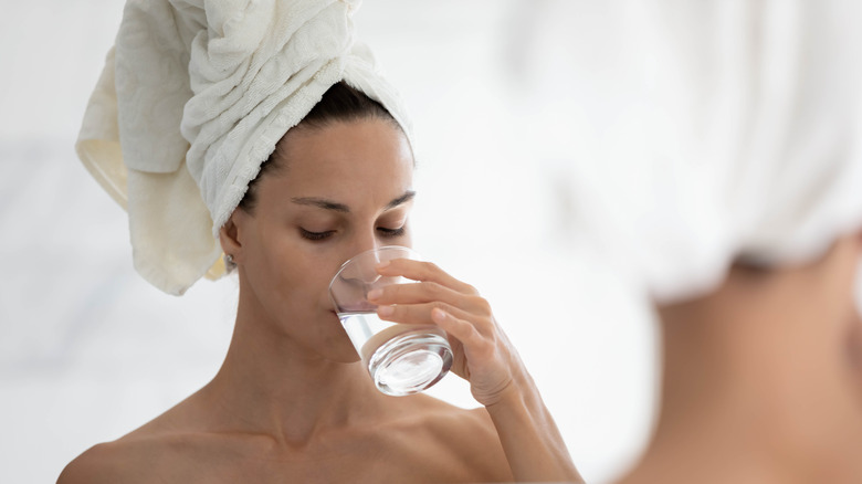 woman wearing towel drinking water