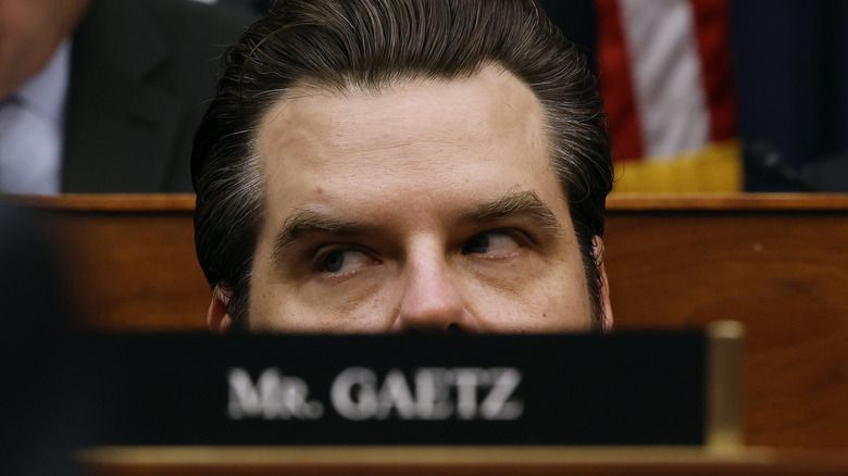 Matt Gaetz appearing to sink lower into his seat during a House meeting