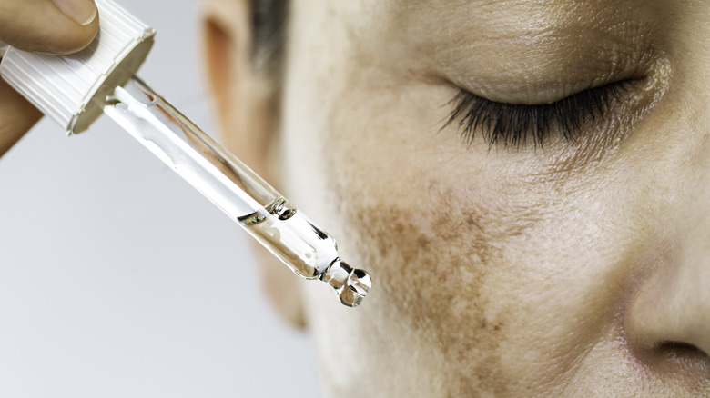 Close up of woman applying serum to face