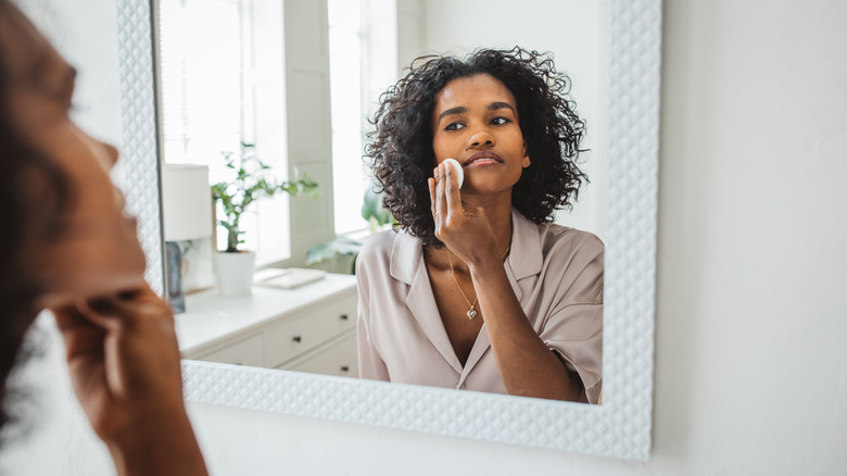 Woman cleaning her face in mirror 