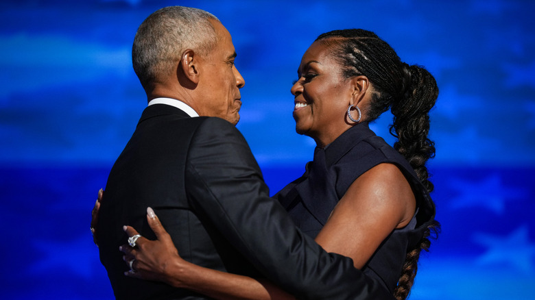 Former U.S. President Barack Obama greets former first lady Michelle Obama as he arrives to speak on stage during the second day of the Democratic National Convention