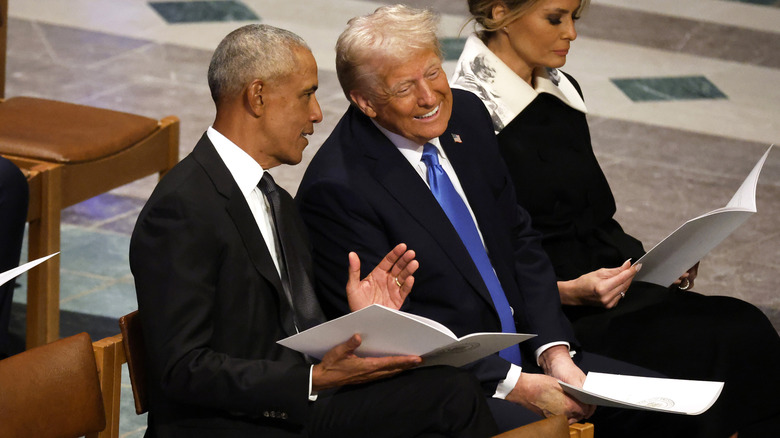 Donald Trump speaks with former U.S. President Barack Obama as Melania Trump looks on during the state funeral for former U.S. President Jimmy Carter