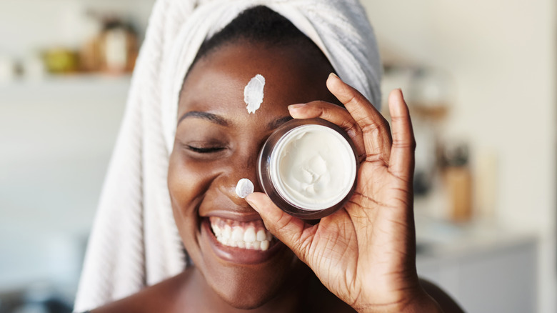 Woman holding small jar of moisturizer