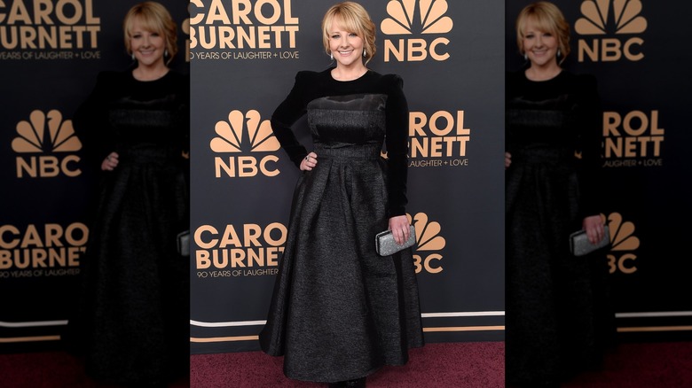 Melissa Rauch on the red carpet wearing a black, strapless gown with a long-sleeve velvet top underneath