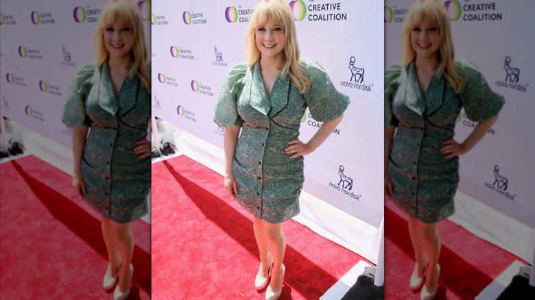 Melissa Rauch on the red carpet in a green print dress