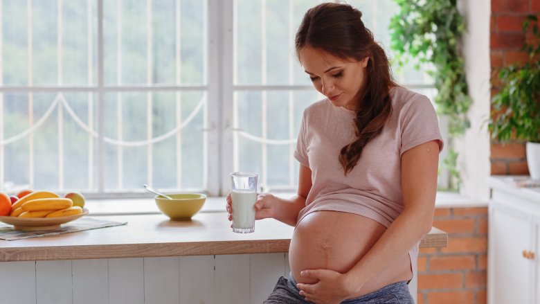 pregnant woman holding glass of milk