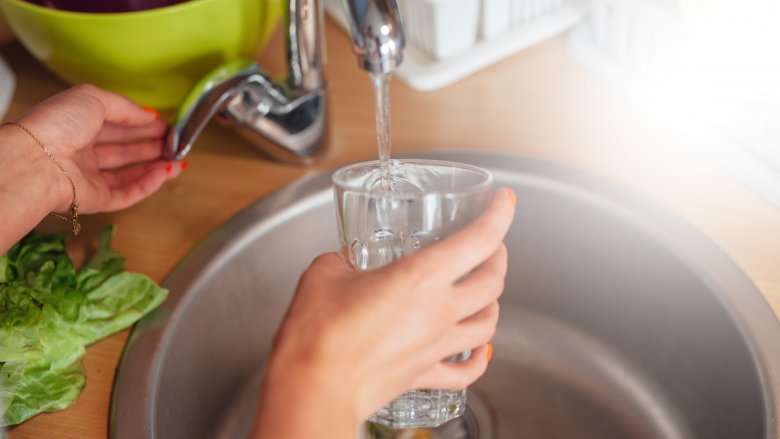 woman filling glass with water from tap