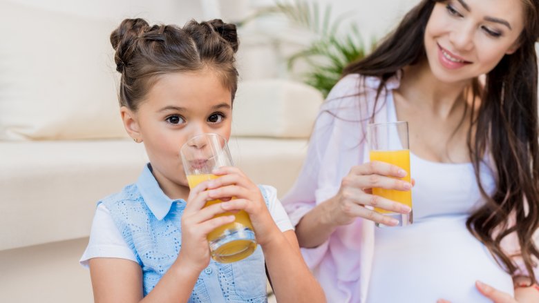 pregnant mother and daughter drinking orange juice