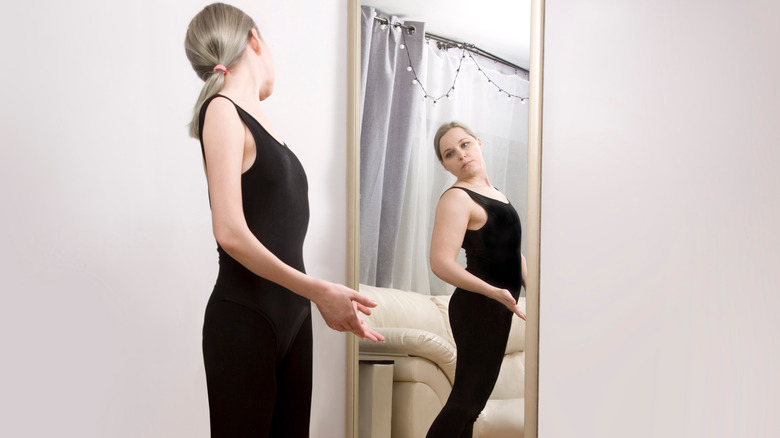 woman looking in mirror with body dysmorphia