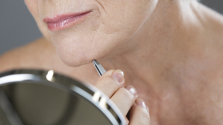 woman plucking facial hairs