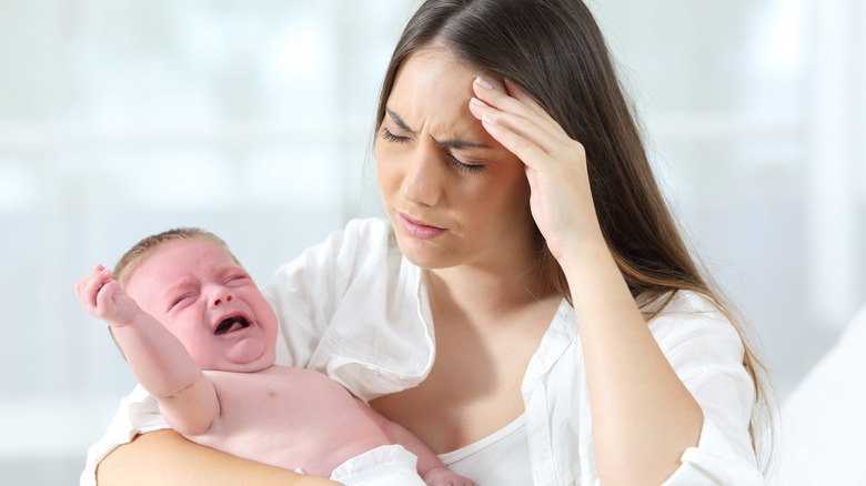 woman with headache holding baby