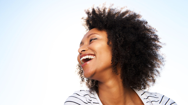 Woman with natural hair smiling away from camera