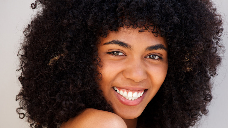 Woman with natural curls smiling at camera