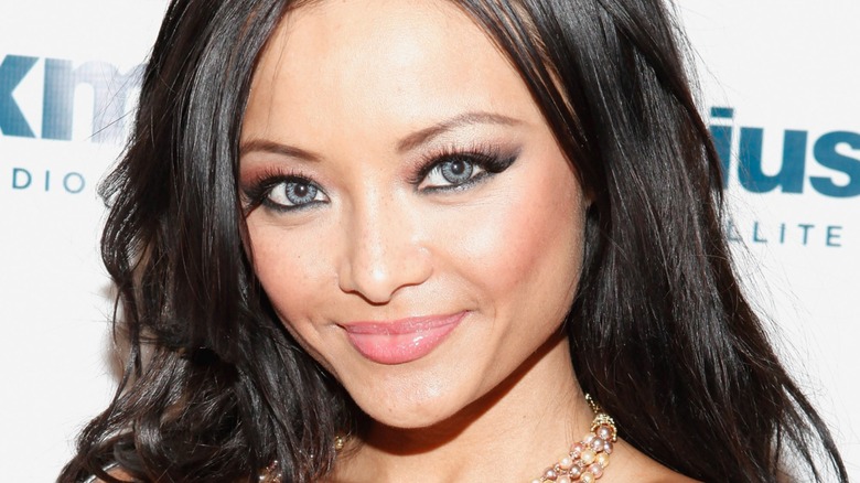 Tila Tequila smiling on a Sirius XM step and repeat with blue contact lenses