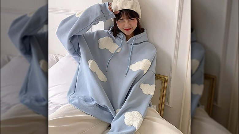 model wearing a blue sweatshirt with white clouds