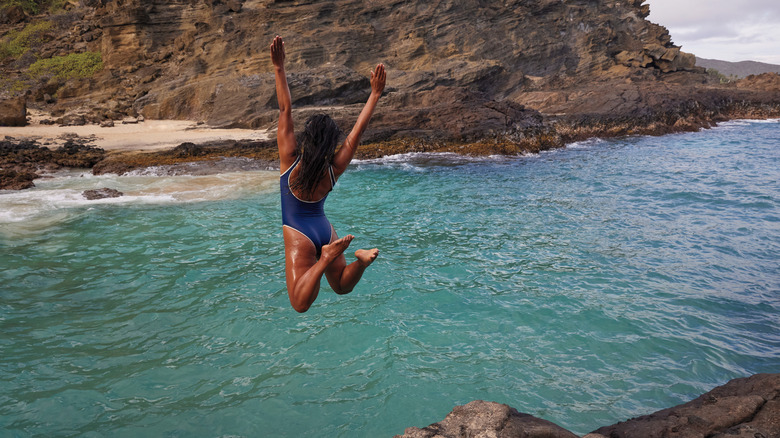 Woman in a swimsuit cliff jumping 