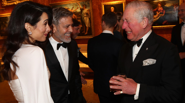 King Charles laughing with Amal and George Clooney. 
