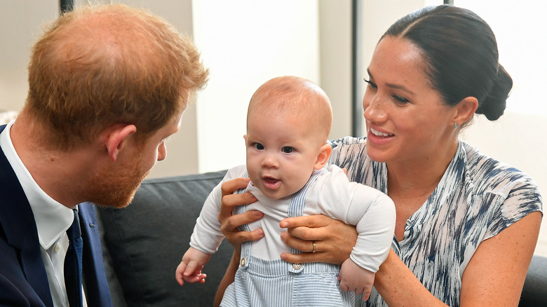 Prince Harry and Meghan Markle holding their son