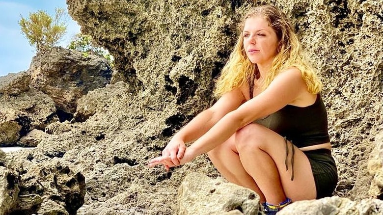 Ariela Weinberg squatting on rock, posing