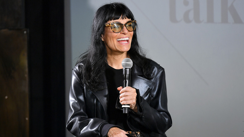 Norma Kamali smiling with a microphone