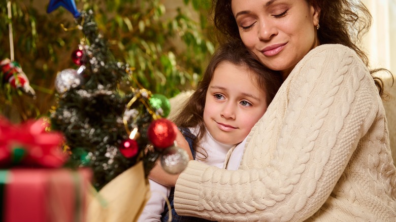 Mom and child hugging by Christmas tree