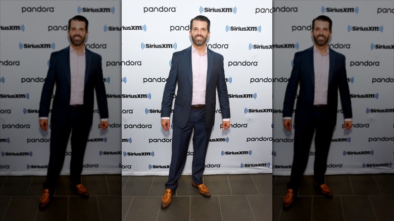 Donald Trump Jr. stands and poses at an event