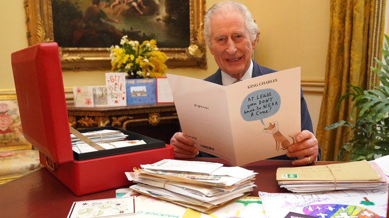 King Charles III smiling with get well cards