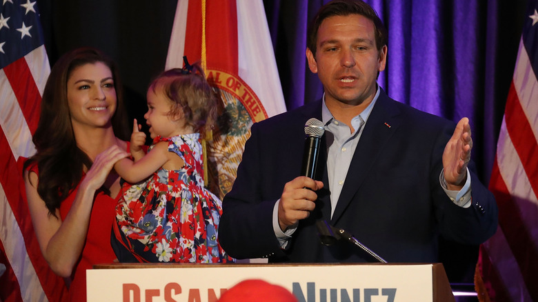 Ron and Casey DeSantis standing at podium with their daughter