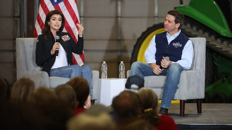 Ron and Casey DeSantis seated, addressing a crowd