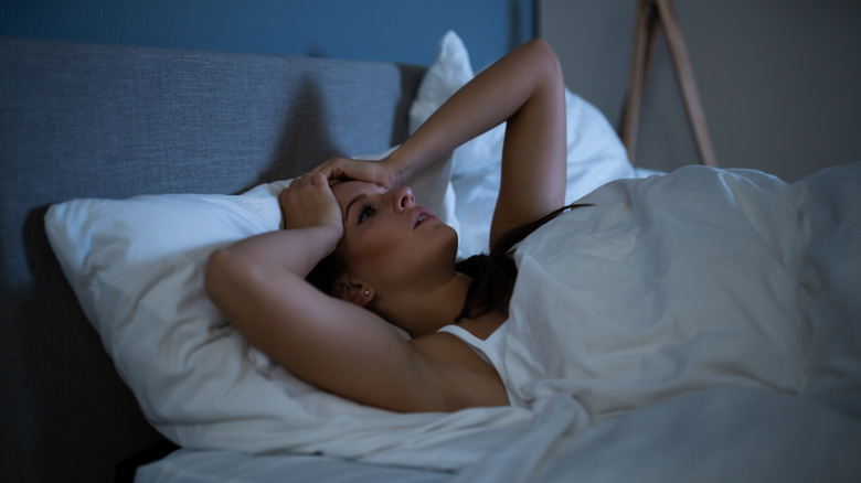 Woman lying in bed, awake, looking troubled