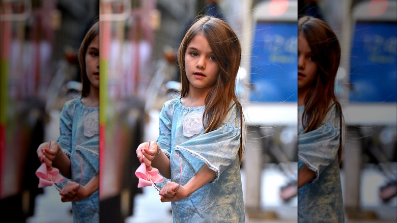 Suri Cruise as a child holding a hairband 