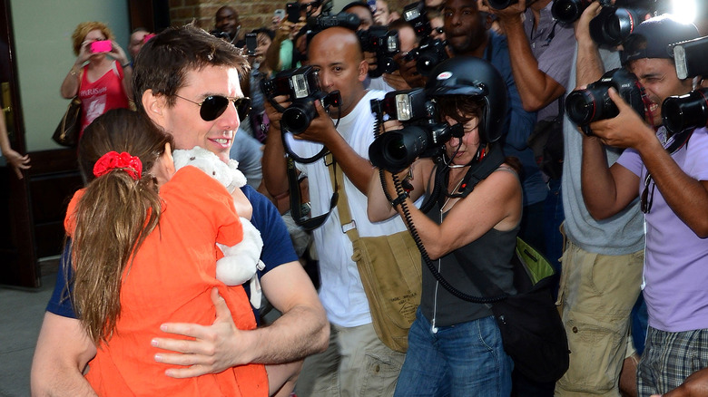 Tom Cruise walks past cameras while holding daughter Suri